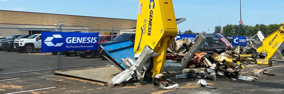 Yellow GXT EVO processing scrap in front of a Genesis logo banner.